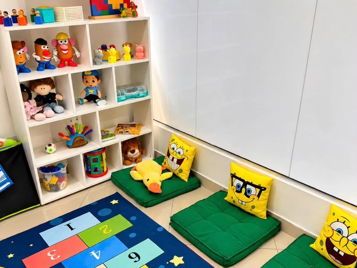 Espaço lúdico da clínica com tapete e materiais para atividades infantis